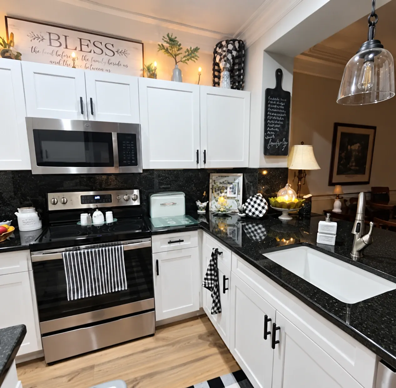 Modern kitchen with white cabinets, black granite countertops, stainless steel appliances, and wood flooring